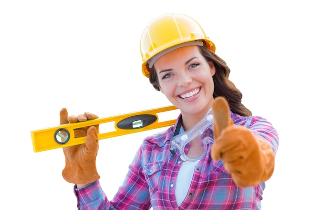 Foto trabajadora de la construcción con los pulgares hacia arriba manteniendo el nivel usando guantes casco duro y gafas de protección en blanco