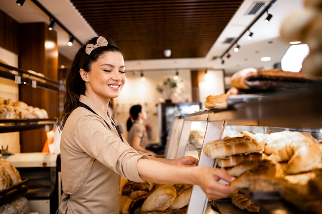 trabajadora de delicatessen uniformada vendiendo pasteles frescos y criada en el departamento de panadería del supermercado