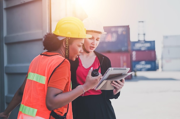 Trabajadora de equipo Mujeres estadounidenses Trabajan en un área de patio de envío internacional Servicio de entrega de exportación e importación con contenedores