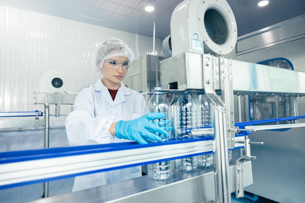 Foto trabajadora en fábrica de agua potable trabajadoras caucásicas trabajo en producción limpia de bebidas cinta transportadora manufactura de agua mineral