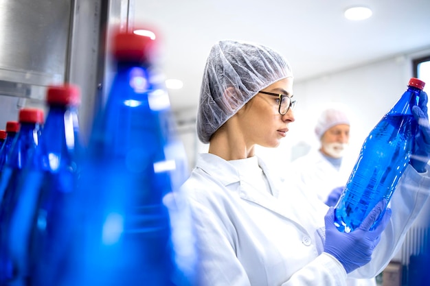 Trabajadora de una fábrica de alimentos comprobando la calidad del producto en la planta embotelladora