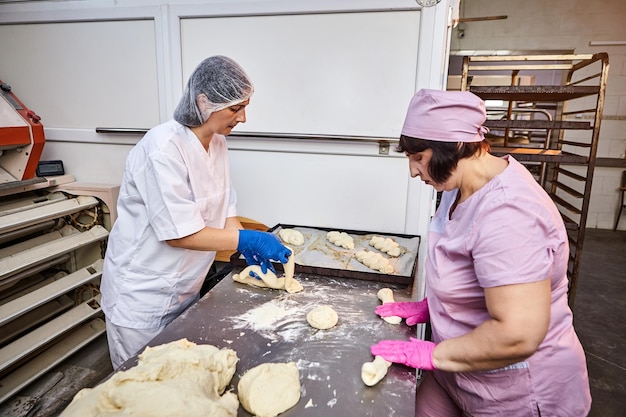 Trabajadora en una gran producción industrial de panadería de productos de panadería en una línea de montaje Mujer de trabajo en equipo en el lugar de trabajo