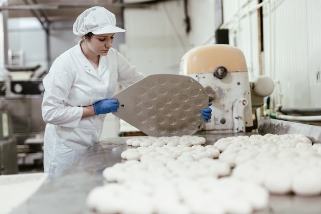 Trabajadora joven que trabaja en panadería grande. Preparación de pan.