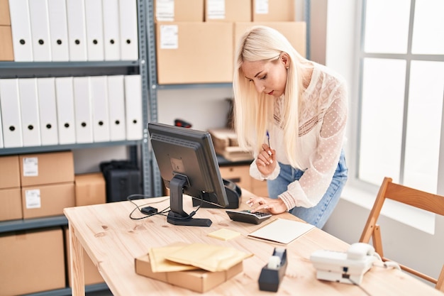 Trabajadora de negocios de comercio electrónico de mujer rubia joven que trabaja en la oficina