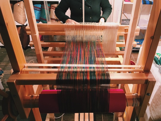 Trabajadora que teje mientras usa el telar en el taller