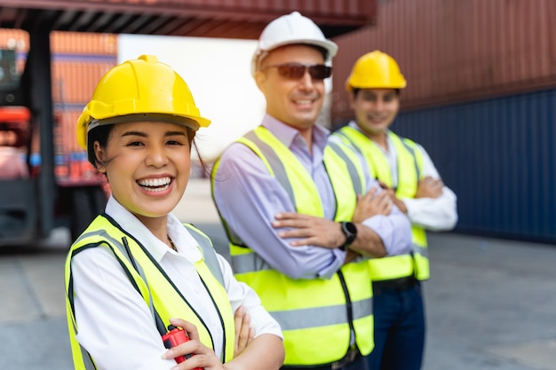 Trabajadora que trabaja con Foreman, de pie con un casco amarillo para controlar la carga y verificar la calidad de los contenedores del buque de carga para importación y exportación en el astillero o puerto