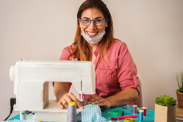 Foto trabajadora que usa la máquina de coser mientras hace máscaras médicas faciales