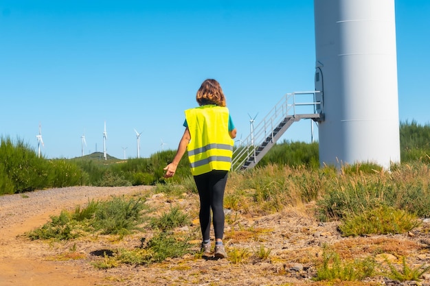 Una trabajadora en una revisión técnica de energía verde de un parque eólico haciendo una llamada de trabajo