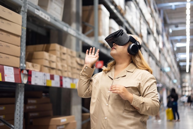 Trabajadora de tamaño plus inspeccionando cajas de productos y utilizando tecnología de realidad virtual para una realidad virtual innovadora mientras trabaja en un gran almacén