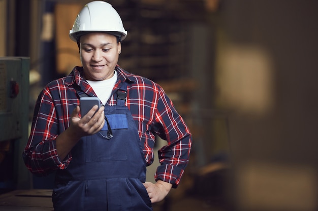 Trabajadora con teléfono inteligente en la planta