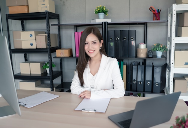 Una trabajadora en traje blanco está trabajando en la oficina.