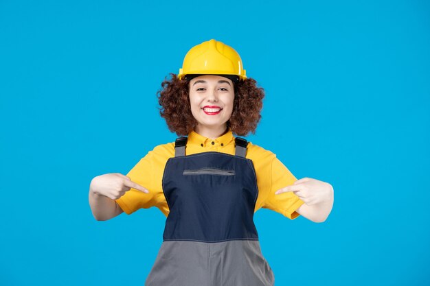 Trabajadora en uniforme amarillo y casco en azul