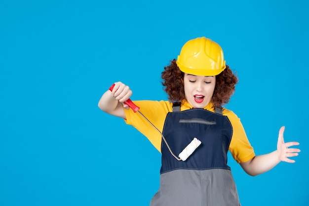 Trabajadora en uniforme con paintroller sobre un azul