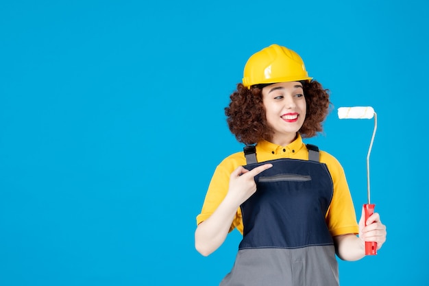 Trabajadora en uniforme con paintroller sobre un azul