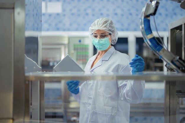 Foto trabajadoras de la fábrica chequean los sistemas de la máquina en la fábrica industrial