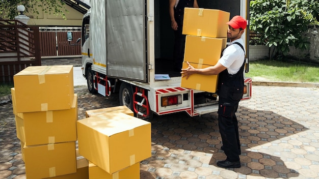 Trabajadores asiáticos y caucásicos en uniforme descargando cajas de cartón del camión