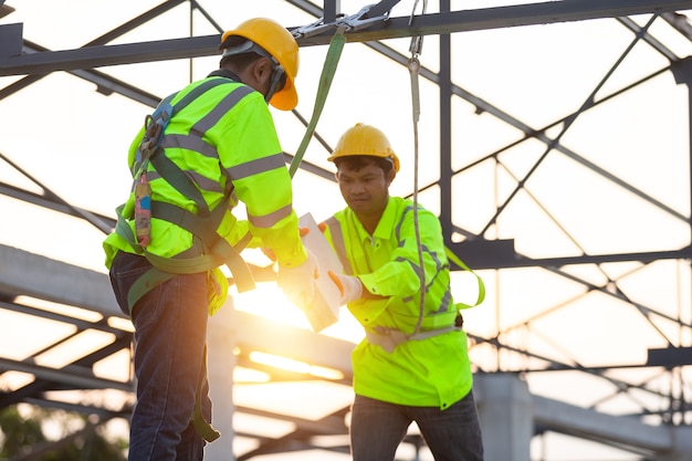 Trabajadores asiáticos usan equipo de seguridad entregándose ladrillos. Concepto de trabajo en equipo en el sitio de construcción.