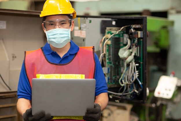 Los trabajadores asiáticos usan una mascarilla desechable para protegerse contra la propagación del virus Corona y el filtro de contaminación del aire por polvo de humo en la fábrica para un cuidado laboral saludable.