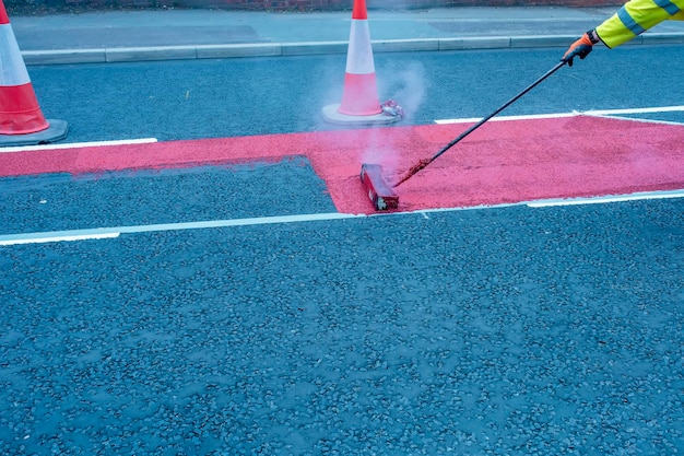 Trabajadores de la carretera que aplican pintura termofusible resistente al tráfico para líneas de señalización vial blancas, amarillas y rojas