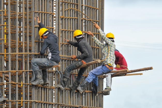 Foto trabajadores de la construcción atando acero