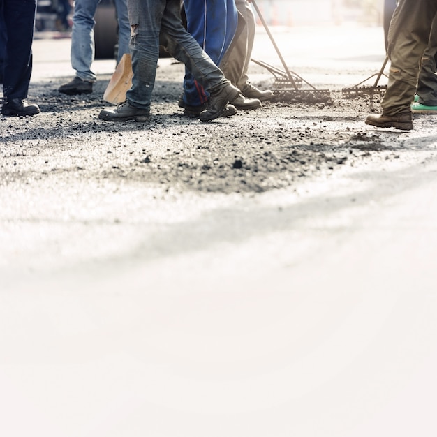 Trabajadores de la construcción de carreteras que reparan la carretera de asfalto.