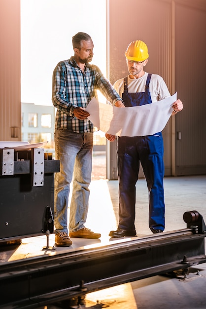 Trabajadores de la construcción comprobando comprobando impresión azul