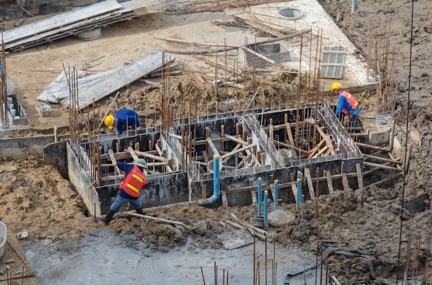 Los trabajadores de la construcción construyen estructuras de acero para mortero de cemento