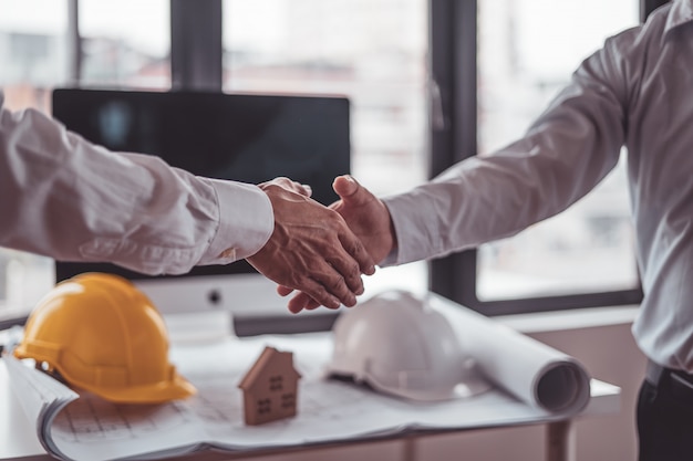 Foto trabajadores de la construcción de ingenieros y arquitectos estrechándose las manos mientras trabajan para el trabajo en equipo en la oficina.