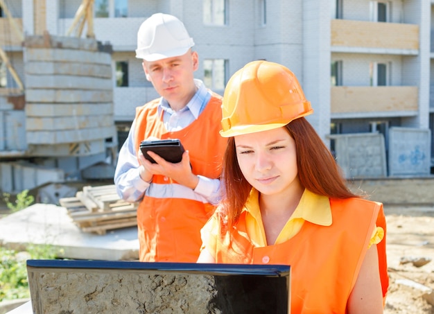 Trabajadores de la construcción masculinos y femeninos mirando portátil