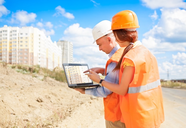 Trabajadores de la construcción masculinos y femeninos mirando portátil