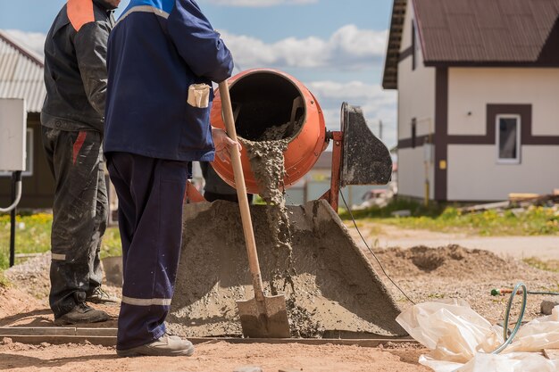 Los trabajadores de la construcción vierten hormigón con una hormigonera.