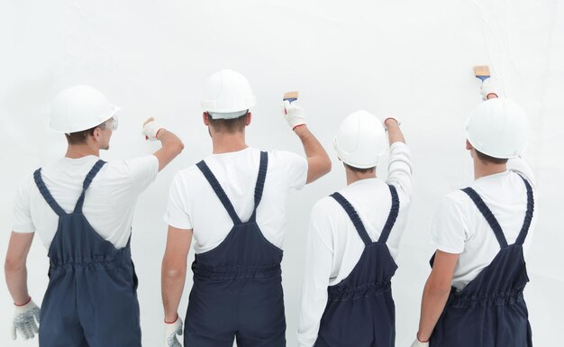 Los trabajadores de la construcción vista trasera pintan la pared aislada en blanco