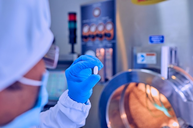 Trabajadores de control de calidad examinando píldoras en laboratorio