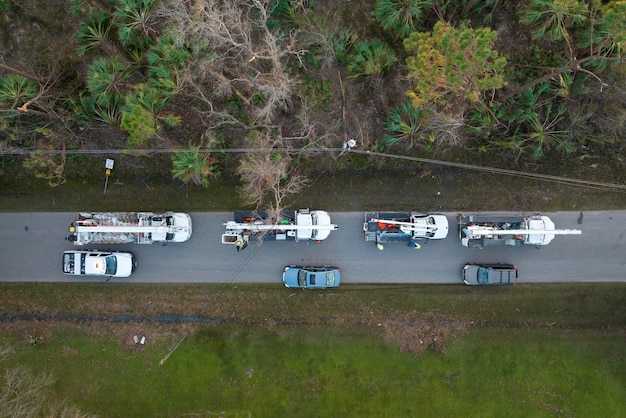 Trabajadores eléctricos reparando líneas eléctricas dañadas usando camiones de cubo después de un huracán en una zona residencial de Florida