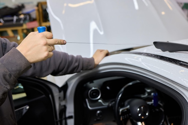 Trabajadores especiales de automóviles quitan el parabrisas viejo o el parbrisas de un automóvil en el garaje de una estación de servicio de automóviles