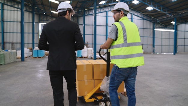 Los trabajadores de la fábrica entregan el paquete de cajas en un carro de empuje en el almacén Concepto de gestión de la cadena de suministro de la industria