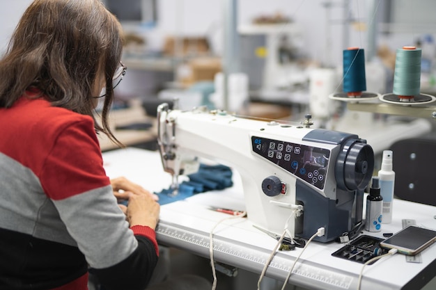 los trabajadores de una fábrica industrial de prendas de vestir cosen ropa en una máquina de coser