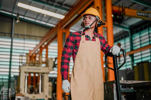 Foto los trabajadores de la fábrica o el técnico controlan la máquina de torno en la fábrica. trabajador asiático que trabaja en ropa de trabajo de seguridad con casco amarillo en el taller de fábrica.