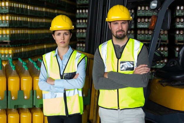 Los trabajadores de la fábrica de pie con los brazos cruzados en la fábrica.