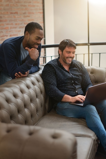 Trabajadores del hombre co discutiendo casualmente ideas en el sofá en lugar de trabajo moderno