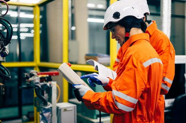 Trabajadores de ingenieros profesionales que trabajan con un sistema de brazo robótico en una fábrica industrial