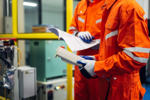 Trabajadores de ingenieros profesionales que trabajan con un sistema de brazo robótico en una fábrica industrial