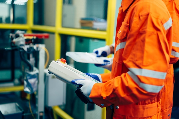 Trabajadores de ingenieros profesionales que trabajan con un sistema de brazo robótico en una fábrica industrial