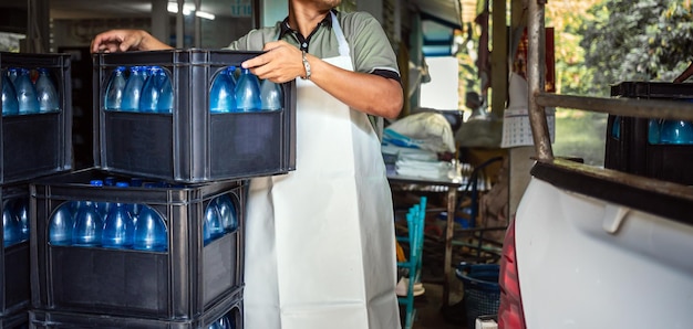 Los trabajadores levantan galones de agua potable azul y botellas en cajas en la parte trasera de un camión de transporte