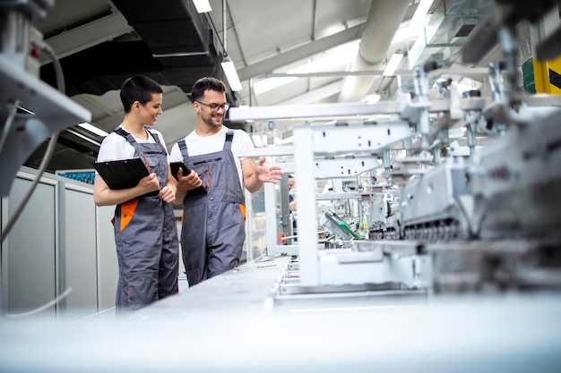 Los trabajadores de la línea de producción que controlan el proceso de la moderna máquina industrial de embalaje en la fábrica