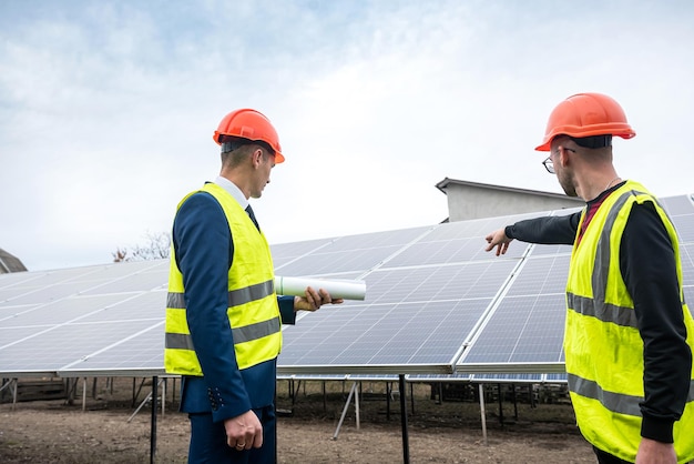 Los trabajadores masculinos fuertes se las arreglan bien con la tarea sobre el plan de instalación de paneles solares. El concepto de electricidad verde y su trabajo.