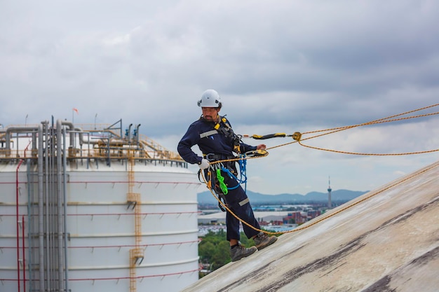 Los trabajadores masculinos limpian el acceso a la cuerda usando la primera línea de seguridad de la cuerda del arnés de seguridad