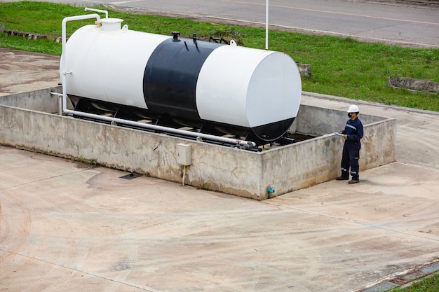 Los trabajadores masculinos son para la inspección de registros de verificación del aceite del tanque de almacenamiento