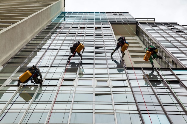 Trabajadores de montañismo industrial se cierne sobre edificio de fachada residencial