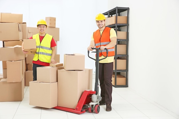 Trabajadores con montones de cajas de dibujos animados en el cargador en el almacén